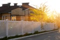 White plastic fence around a typical house in a cottage village. Concept of landscaping, protection, fencing of a territory