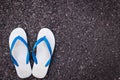 White plastic flip flop shoe on black asphalt road