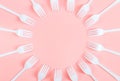 White plastic forks are arranged in a round frame on a light pink background. Royalty Free Stock Photo