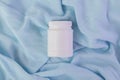 White plastic jar with vitamins and bioactive additives. Useful pills for youthful skin on a beautiful blue background with copy