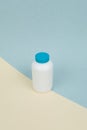 White plastic medical container for tablets or capsules on a yellow-blue background Royalty Free Stock Photo