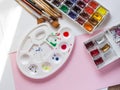 palette with a set of watercolor paints and brushes on a pink background, the artist`s tools Royalty Free Stock Photo