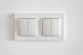 White plastic pass-through electricity switches on a white wall