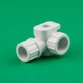 White plastic pipe fitting on a green background. It features two cylindrical connectors Royalty Free Stock Photo