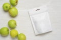 White plastic pouch bag with apples on wood table. 3d rendering