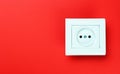 White plastic power socket on red background. Wall with copy space. Minimalism. Royalty Free Stock Photo