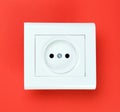 White plastic power socket on red background. Wall with copy space. Minimalism. Royalty Free Stock Photo