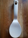 White plastic rice spoon on a wooden background