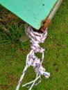 White plastic rope tied and knotted at the end of the green iron table pole. Royalty Free Stock Photo