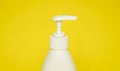White plastic soap or shampoo dispenser pump bottle isolated on yellow background. Skin care lotion. Bathing essential Royalty Free Stock Photo