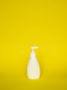 White plastic soap or shampoo dispenser pump bottle isolated on yellow background. Skin care lotion. Bathing essential Royalty Free Stock Photo
