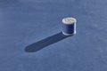 A white plastic spool of sewing thread in a beautiful pale blue color stands on a harmonious blue background. Royalty Free Stock Photo