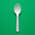 White plastic spoon centered against a solid green background. The spoon has a slig Royalty Free Stock Photo
