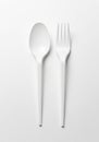 White plastic spoon and fork placed side by side on a plain white background. The Royalty Free Stock Photo