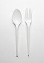 White plastic spoon and fork on a plain white background arranged vertically side by Royalty Free Stock Photo