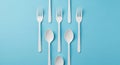 White Plastic Spoons and Forks Arranged in a Symmetrical Pattern on a Blue Background cutlery Royalty Free Stock Photo