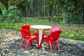 White plastic table with red chairs in a cafe in the autumn park. Closing season Royalty Free Stock Photo