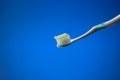 White plastic toothbrush with light blue toothpaste. Close up studio shot, isolated on blue background, no people Royalty Free Stock Photo