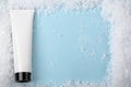 White plastic tube of cream, lotion on a blue background with snow. Beauty skincare product top view. Winter cosmetics for dry Royalty Free Stock Photo