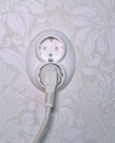white plastic wall socket on wallpaper with one plug Royalty Free Stock Photo