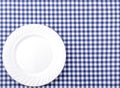 White Plate on Blue and White checkered Fabric Tablecloth Background.