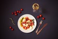 White plate with caprese salad, glass of white wine and cherry tomatoes near. Top view