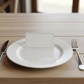 A white plate is centered on a wooden dining table. On the plate, a blank, rectangular Royalty Free Stock Photo