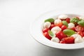 White plate of classic delicious caprese salad with ripe tomatoes, mozzarella and fresh basil leaves on gray background with copy Royalty Free Stock Photo