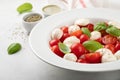 White plate of classic delicious caprese salad with ripe tomatoes, mozzarella and fresh basil leaves on gray background. Italian f Royalty Free Stock Photo