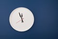 White plate clock on a blue background with copy space. The hands point to 12 o`clock. Interval fasting or autophagy