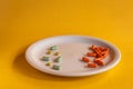 White plate with colored medications on a orange background. Pharmaceutical drug overdose concept Royalty Free Stock Photo