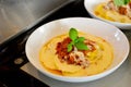 White plate with colorful italian pasta Bolognese, creamy yellow sauce and green basil.