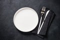White plate, cutlery and napkin on black table top view. Royalty Free Stock Photo