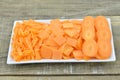 White plate with different slices carrots on wooden table, closeup Royalty Free Stock Photo