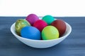 White plate of Easter versicolored boiled eggs on grey wood