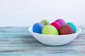 White plate with Easter versicolored boiled eggs on wooden background