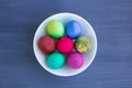 White plate with Easter versicolored eggs on grey wooden background