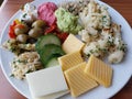 A plate filled with a variety of cheese and Cold salads