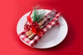 Christmas dinner. White plate, fork, knife and Christmas decoration on red background Royalty Free Stock Photo