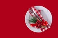 Christmas dinner.White plate, fork, knife and Christmas decoration on red background Royalty Free Stock Photo