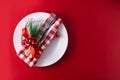 Christmas dinner. White plate, fork, knife and Christmas decoration on red background Royalty Free Stock Photo