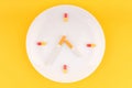 A white plate in the form of a clock with arrows of cigarettes, instead of the numbers of pills and pills Royalty Free Stock Photo