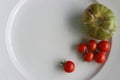 White Plate with fresh vegetables on wooden table. Two cucumbers, red cherry tomatoes, green cracked tomato with vertical splits, Royalty Free Stock Photo