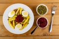 Plate with fried potato, egg, green peas and beetroot caviar, bowls with beetroot and green peas, fork on table. Top view