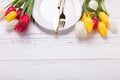 White plate, golden cutlery and white and red tulips flowers on