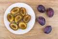 White plate with halves of plums and whole plums Royalty Free Stock Photo