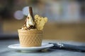White plate with ice cream dessert in wafer cup with chocolate cookies and creative decoration topping on blurred colorful Royalty Free Stock Photo