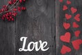 The word Love on a rustic background with red cardboard hearts on the side as a symbol of Valentine`s Day