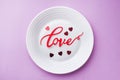 White plate inscription love on a pink background. Concept Valentine`s day