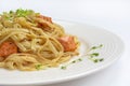 Fettuccine pasta with salmon on a white plate, on a wooden background, next to a basket with greens and cutlery: a spoon and a for Royalty Free Stock Photo